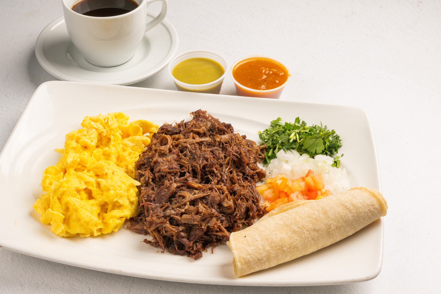Breakfast plate with shredded beef, eggs, and a tortilla