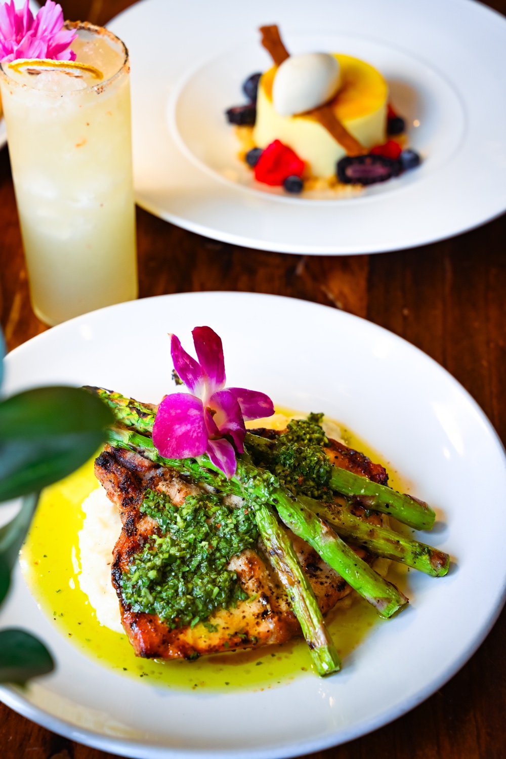 Plated entrée with asparagus, with a drink and dessert nearby