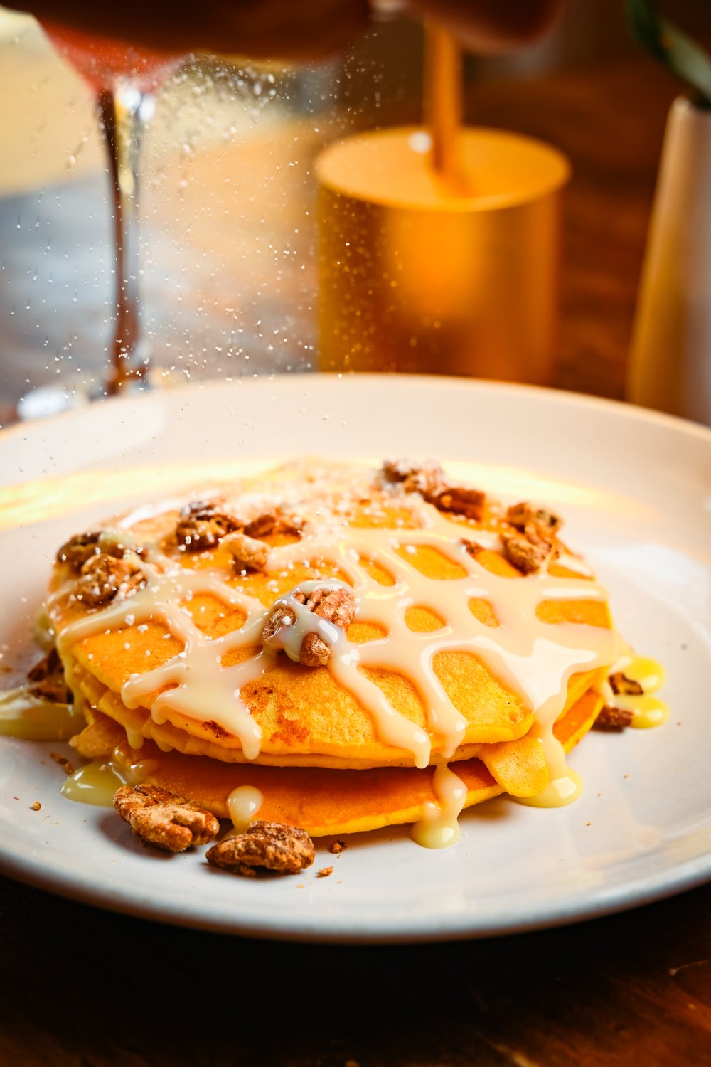 Icing being poured over a plated stack of pancakes