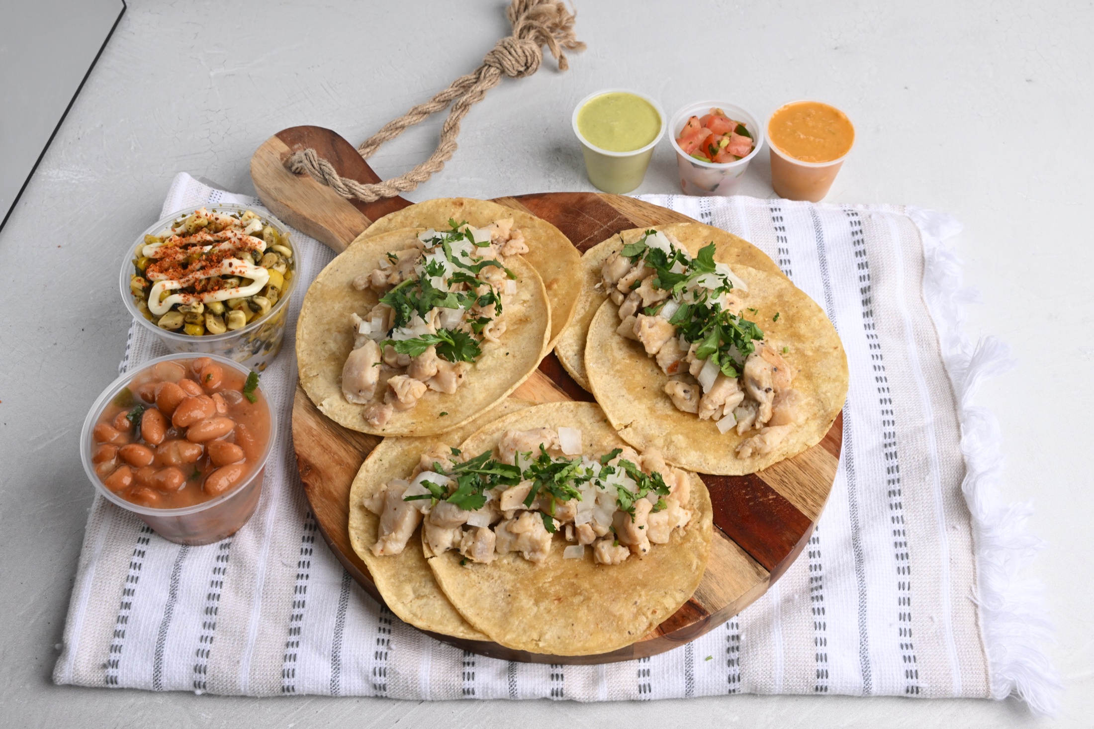 Three chicken tacos with beans, corn, and salsa cups