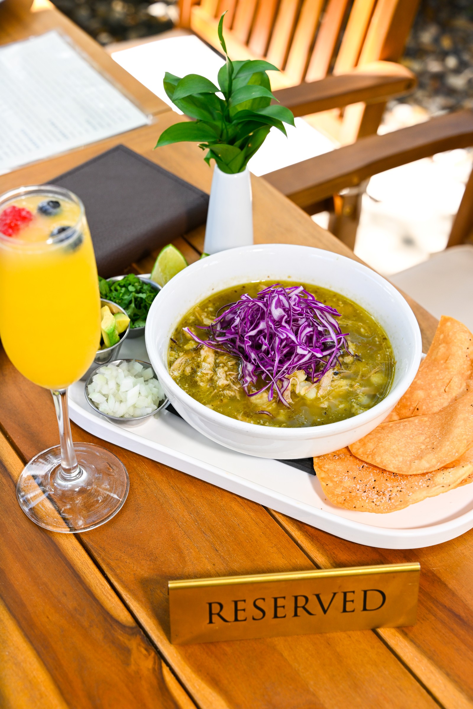 Soup topped with shredded cabbage, with chips and a citrus drink