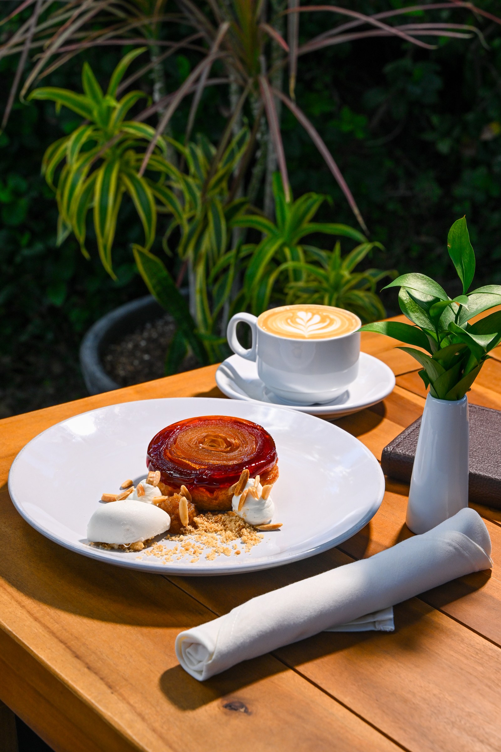 Caramelized apple tart with ice cream and almond garnish, served with a latte