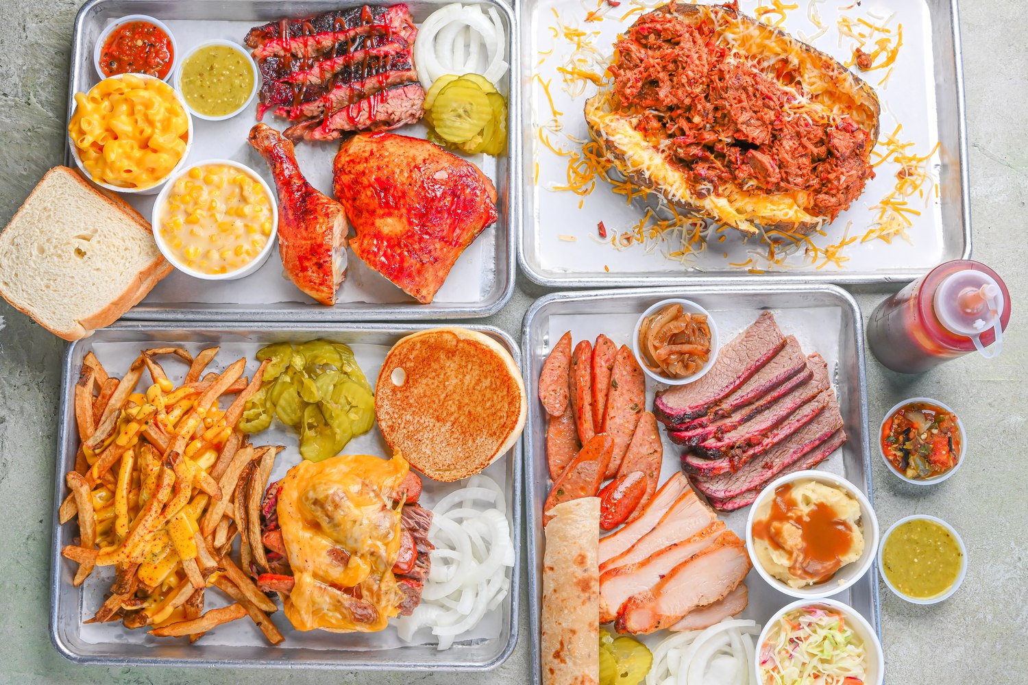 Several BBQ platters with smoked meats, sides, and bread