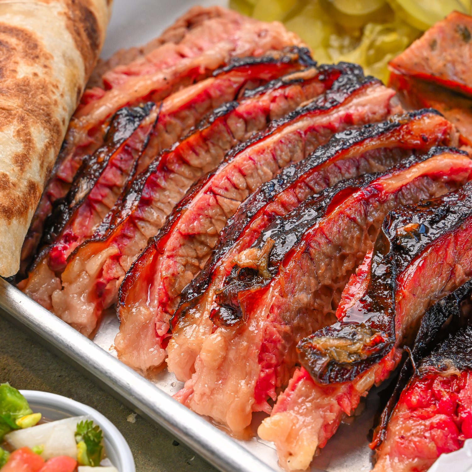 Close view of sliced smoked meat with bread and sides