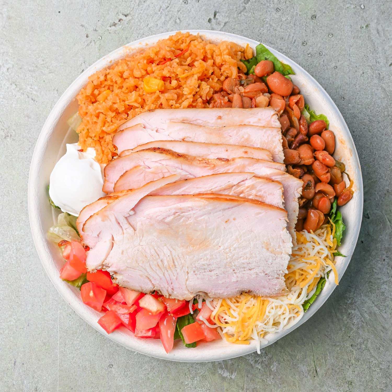 Plate of sliced smoked meat with rice, beans, tomato, and lettuce
